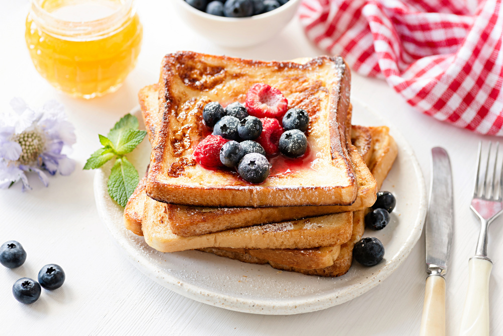 French toast with berries on white plate